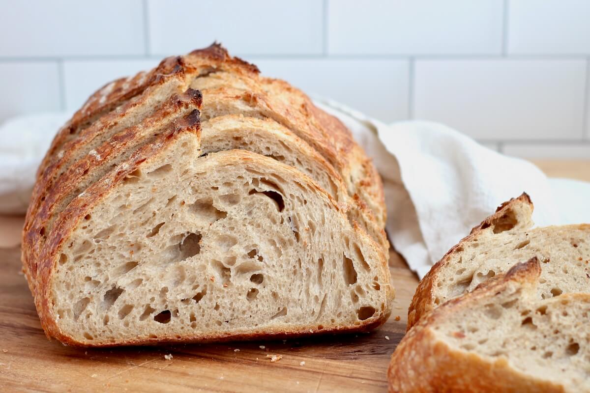 A sliced loaf of beer sourdough bread on a wooden cutting board.