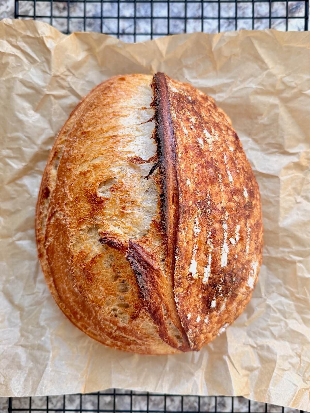 A baked loaf of beer sourdough bread on a wire cooling rack.