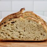 Slices of pesto sourdough bread on a wooden cutting board.