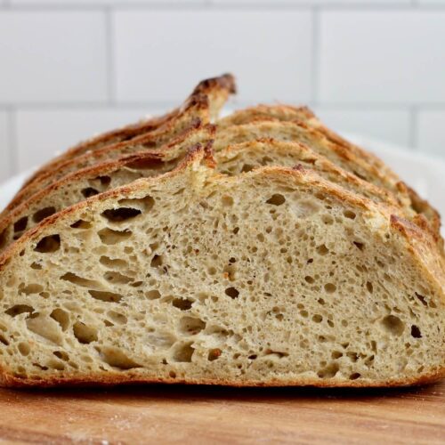 Slices of pesto sourdough bread on a wooden cutting board.