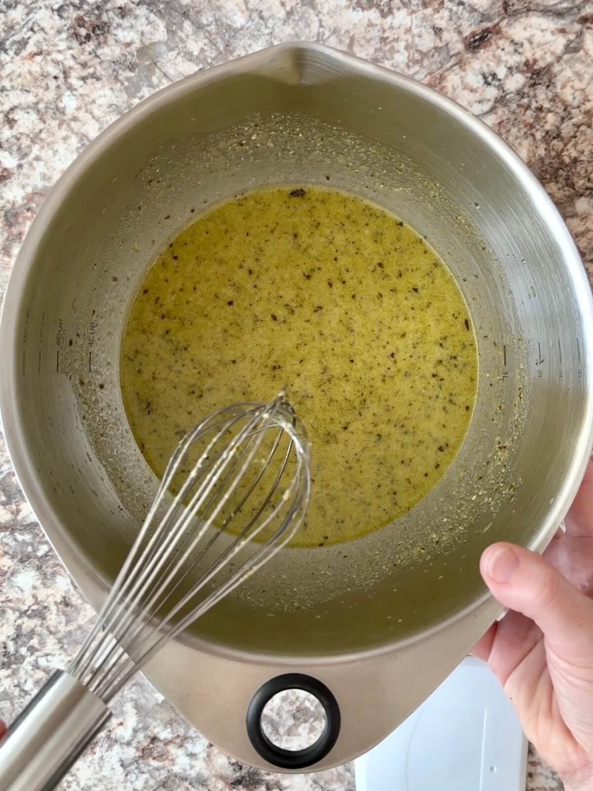 Water, pesto, and active sourdough starter whisked together in a bowl.