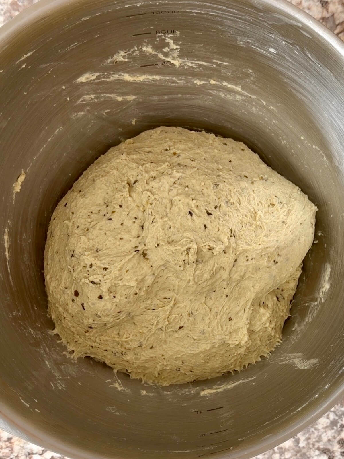 Pesto sourdough bread dough after being stretched and folded in a mixing bowl.