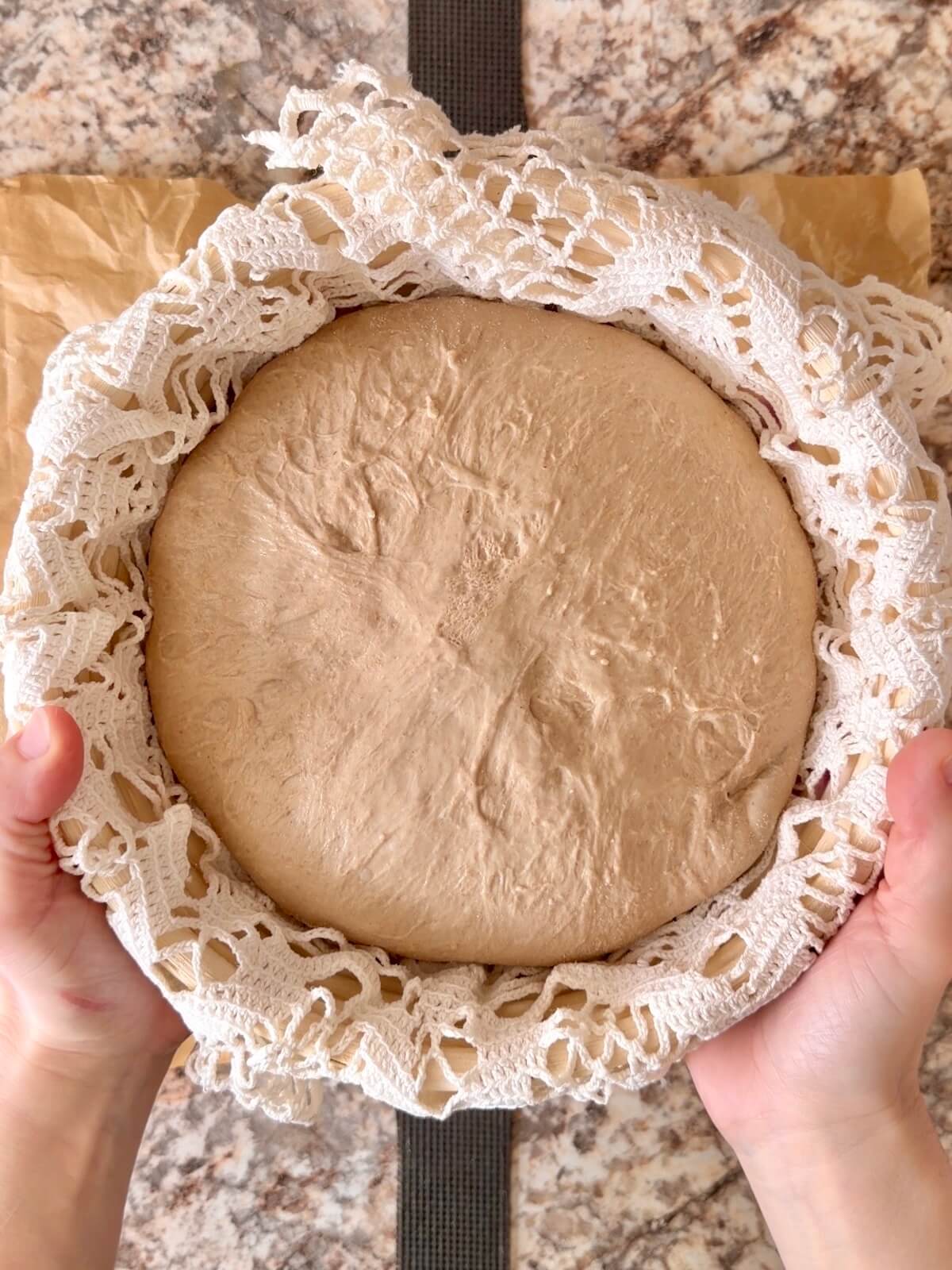 Root beer sourdough bread dough in a round proofing basket after cold proofing overnight.