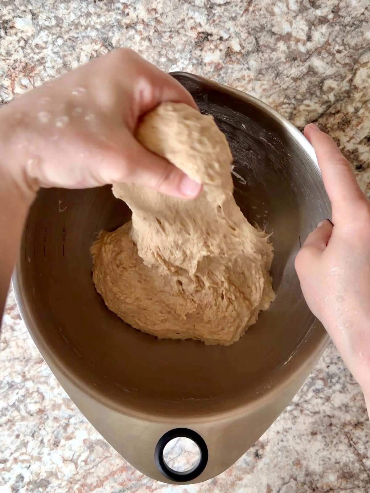 Root beer sourdough bread dough being stretched and folded in a bowl.