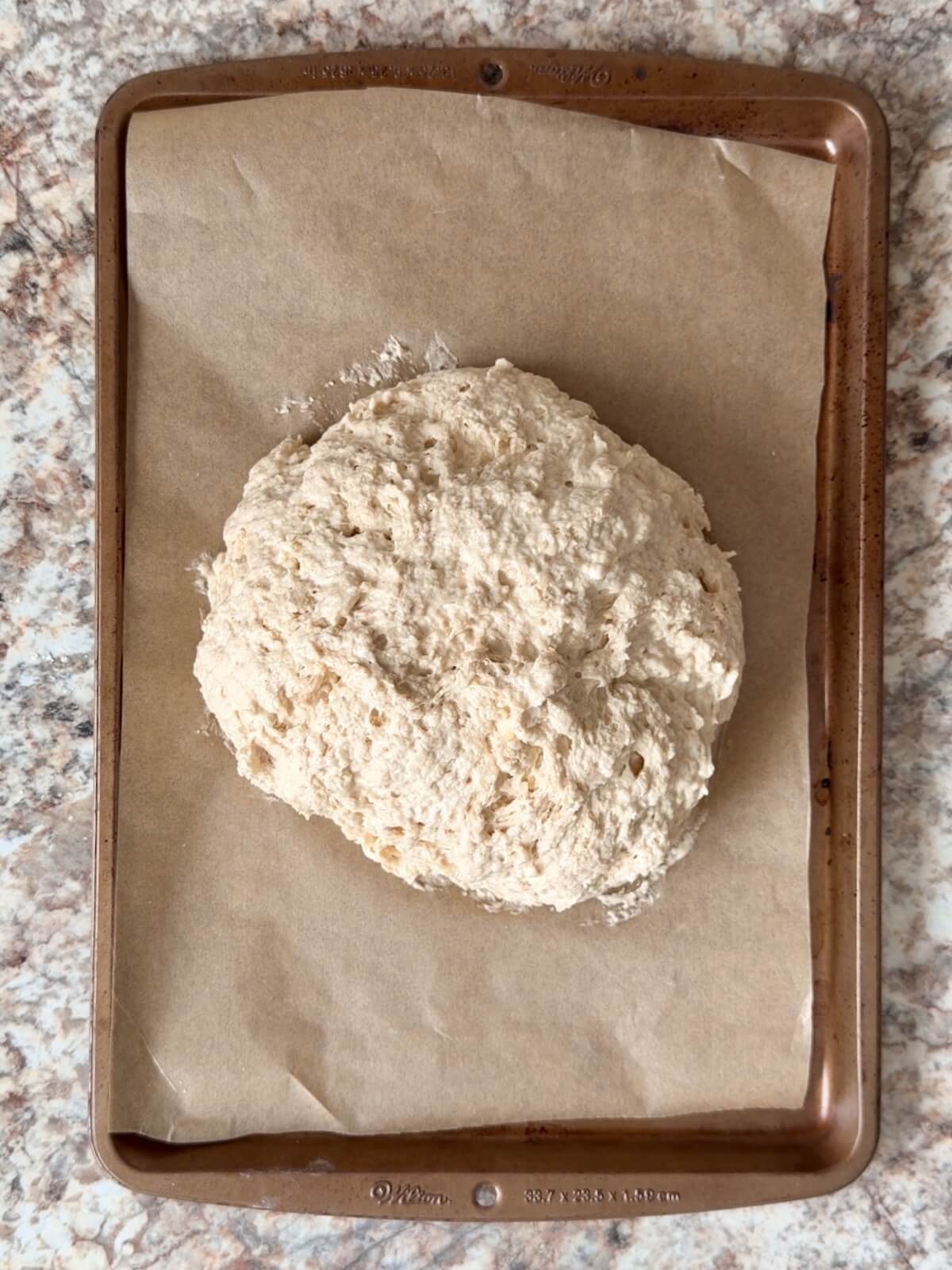 Sourdough Irish soda bread dough on a parchment-lined baking sheet.