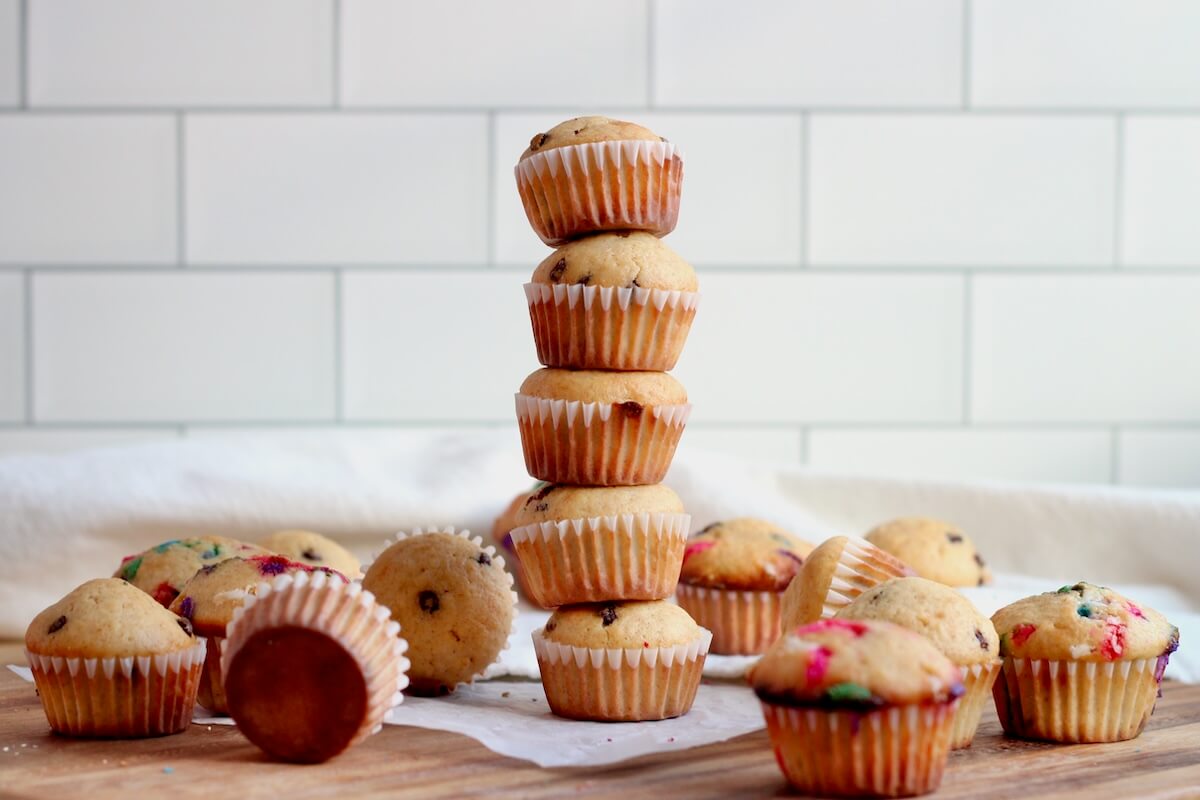 Five mini sourdough muffins stacked on top of each other with several more scattered around the stack.