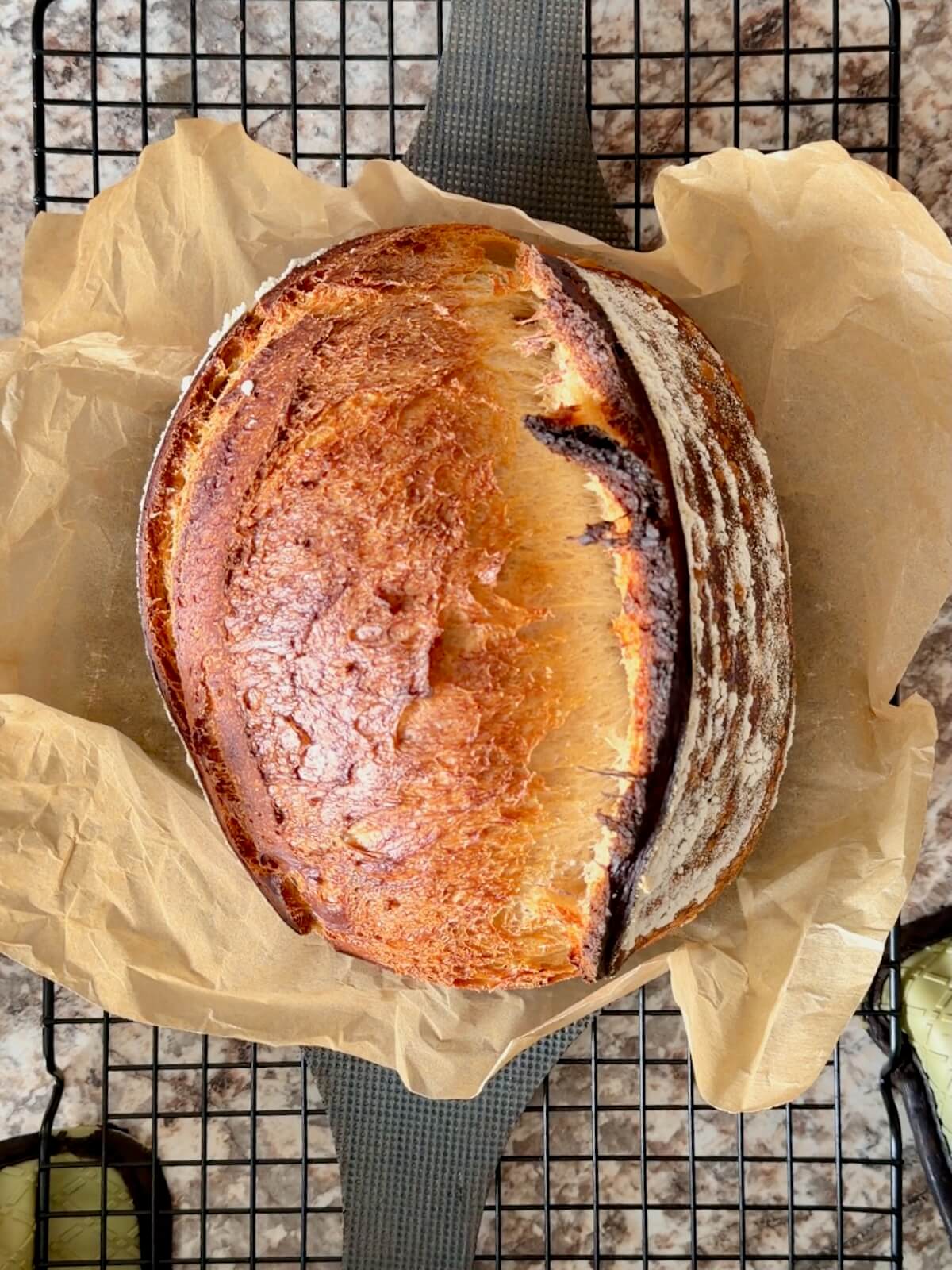 A baked loaf of high protein sourdough bread on a wire cooling rack.