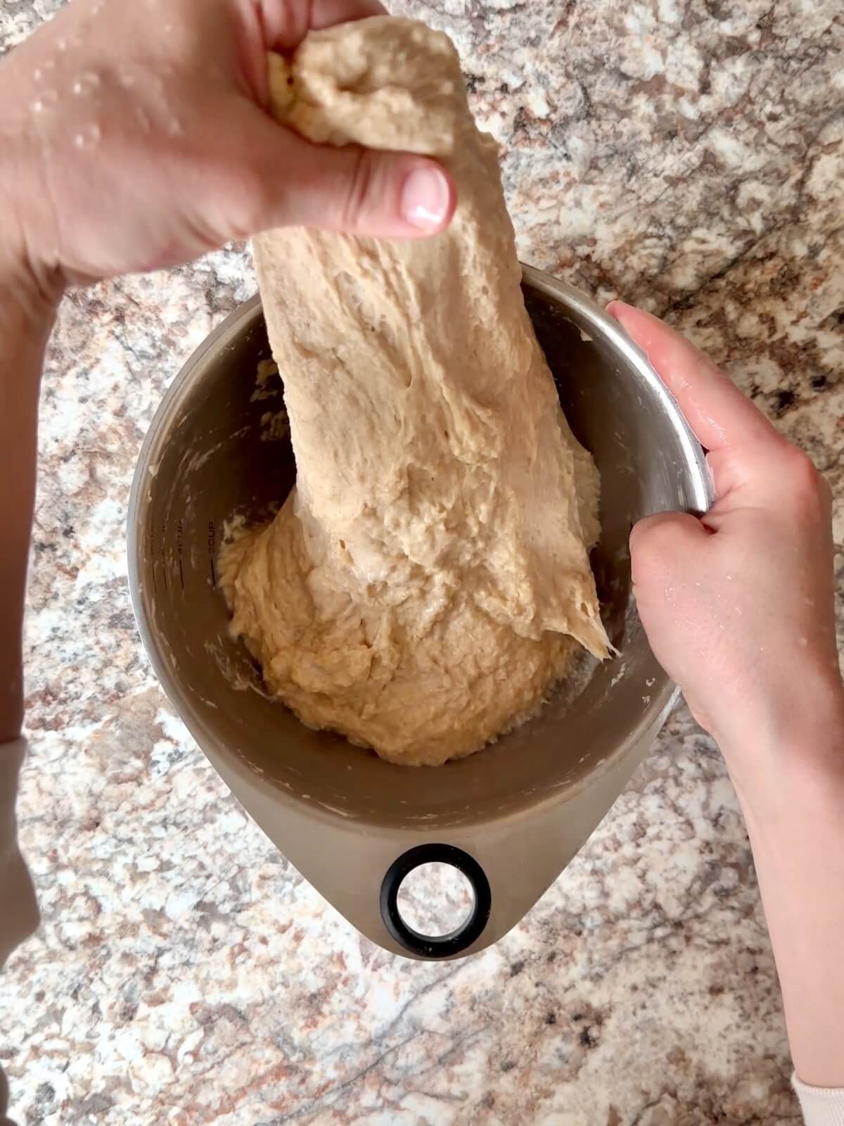 Dough being stretched and folded in a mixing bowl.