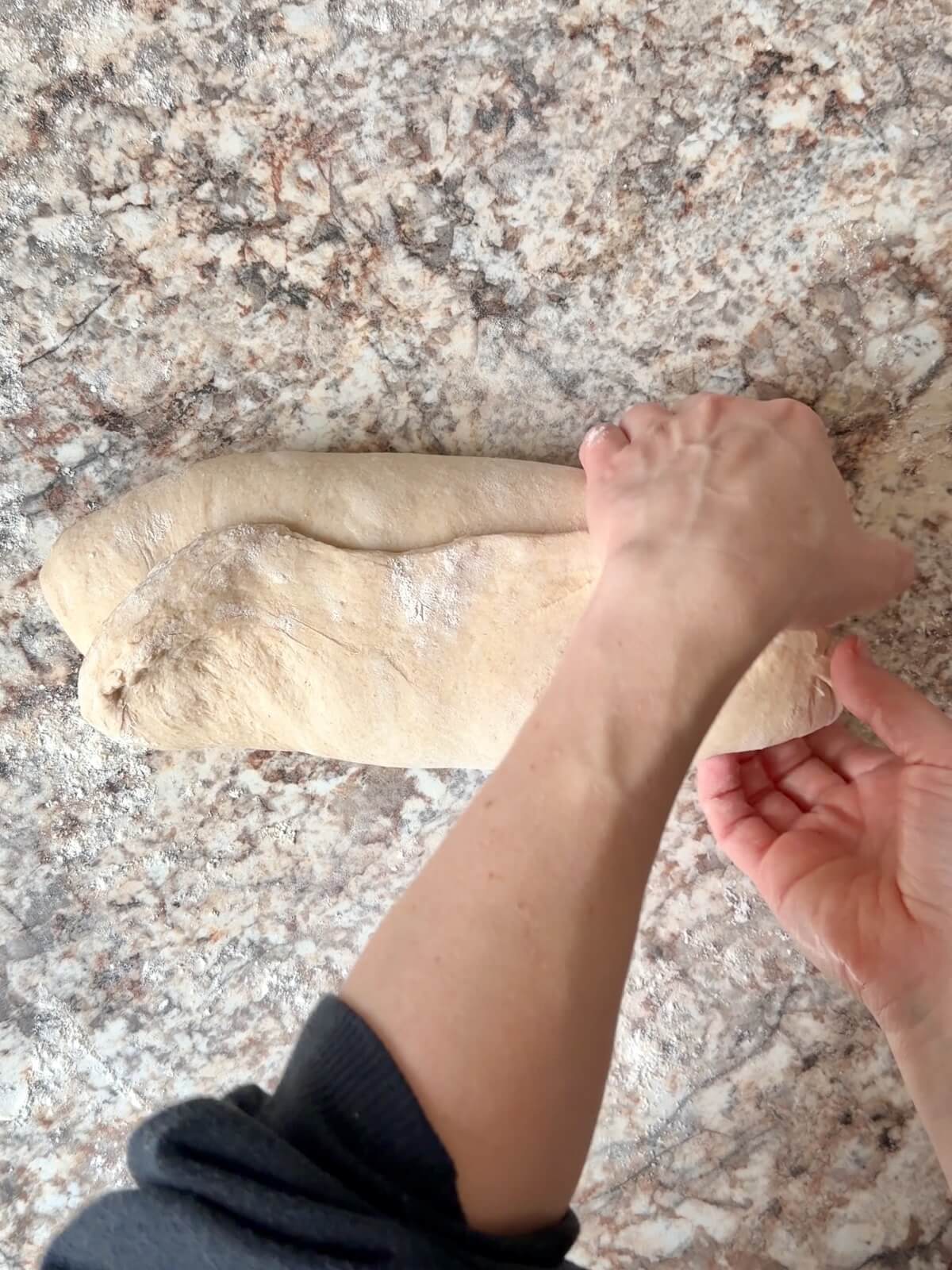 Two hands shaping bread dough.
