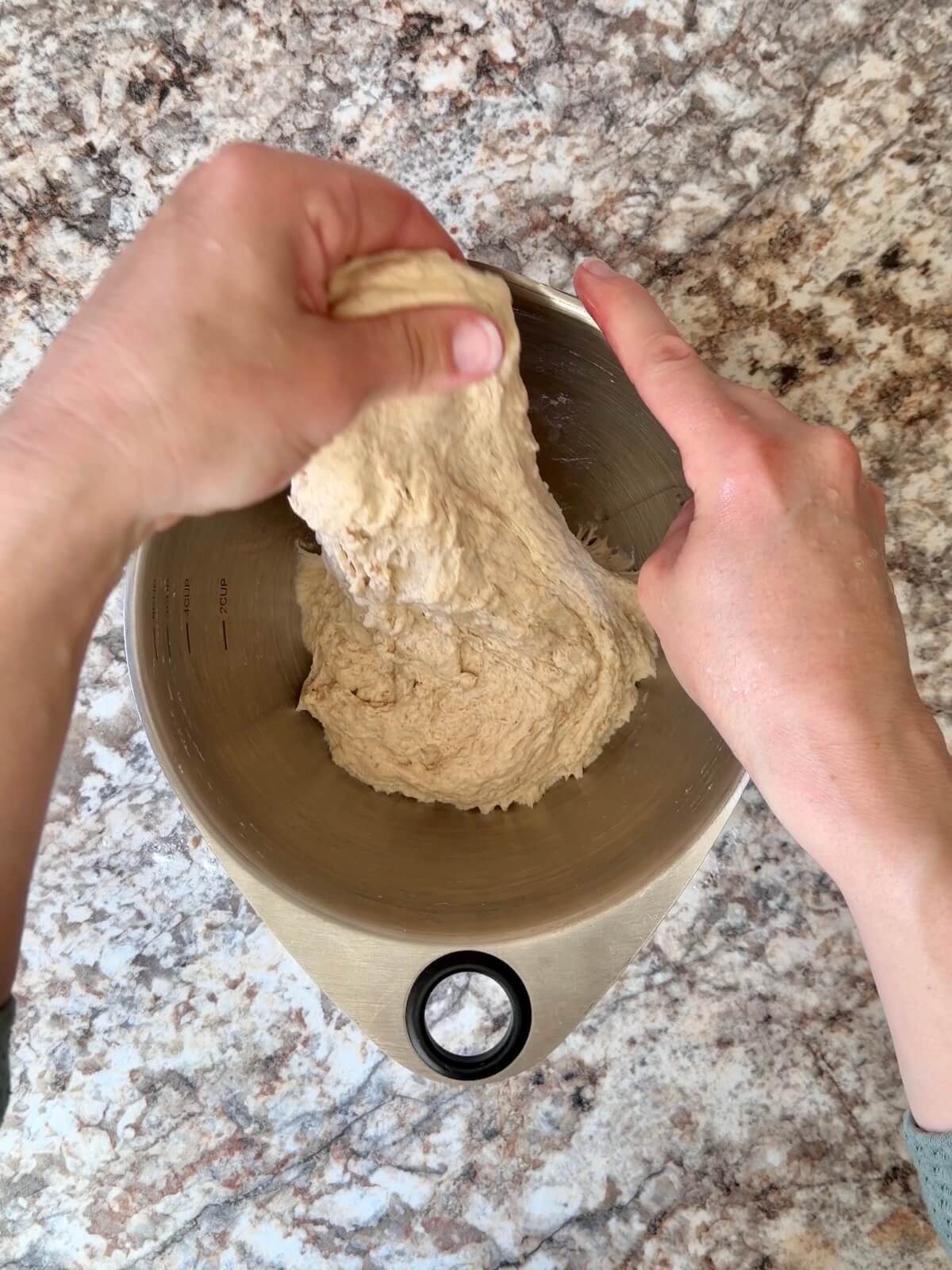Sourdough beer pizza dough being stretched and folded in a bowl.