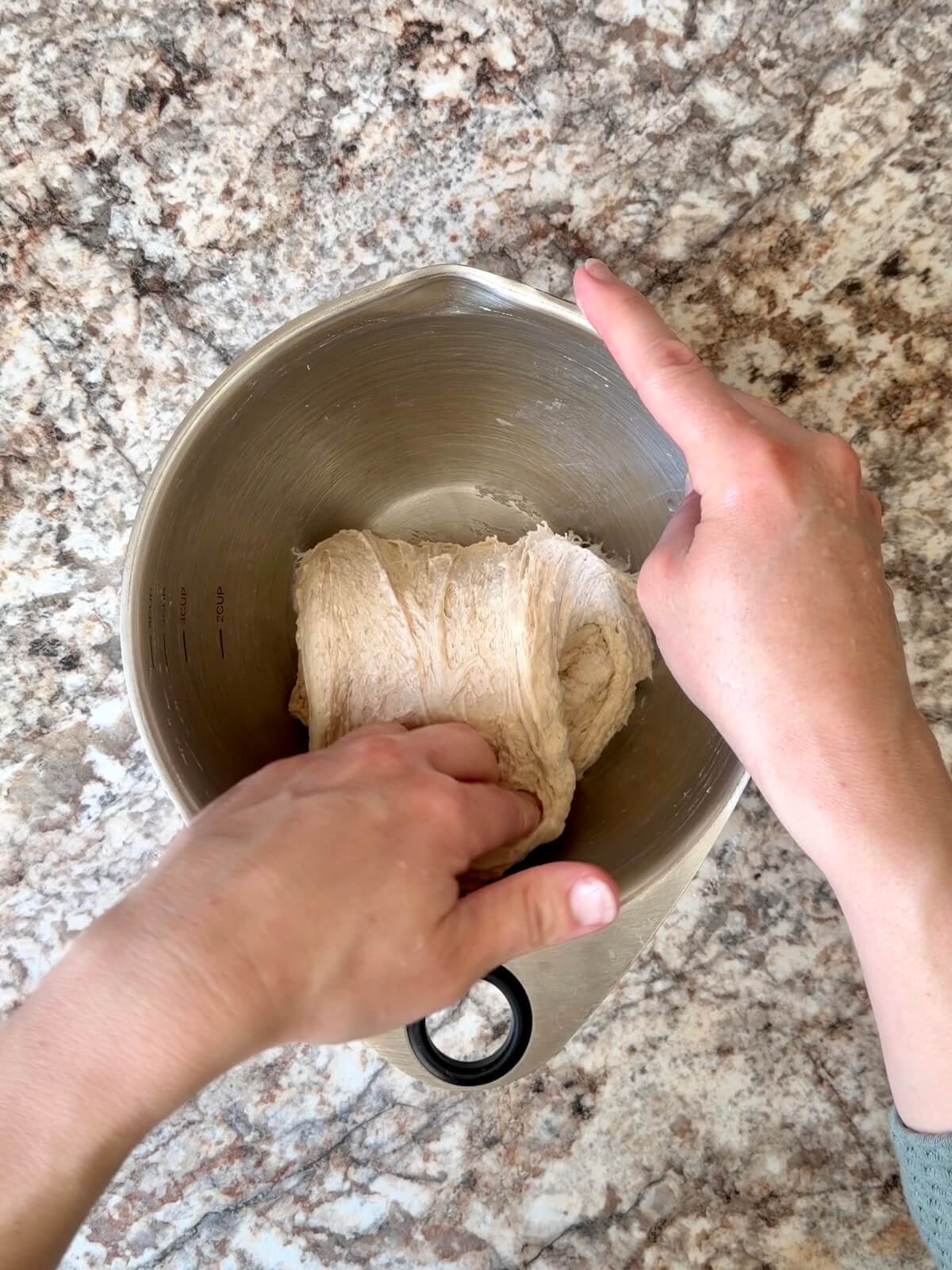 Sourdough beer pizza dough being stretched and folded in a bowl.