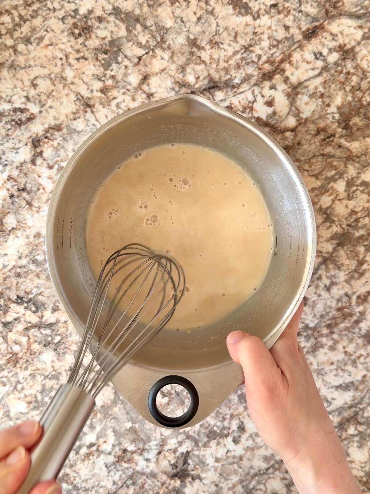 Water, sourdough starter, and vanilla extract whisked together in a bowl.