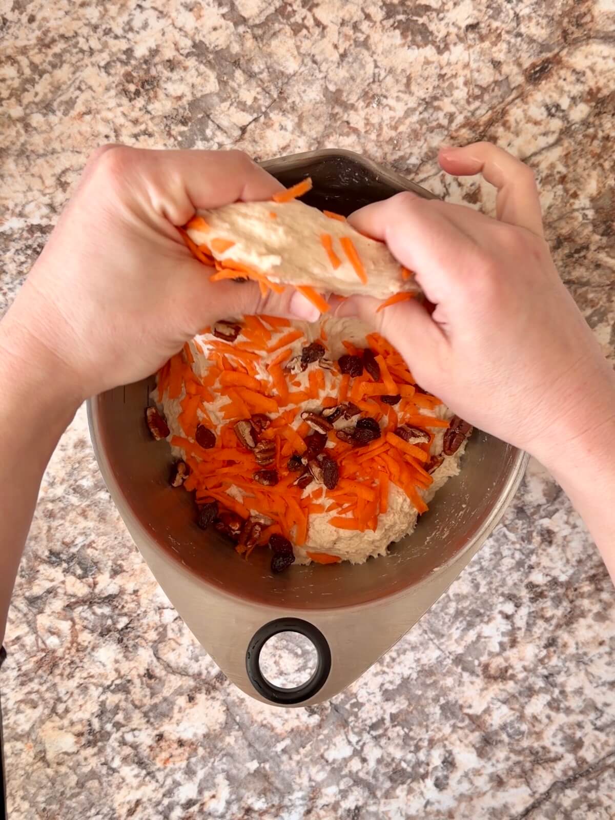 Shredded carrots, raisins, and pecans being folded into the dough.