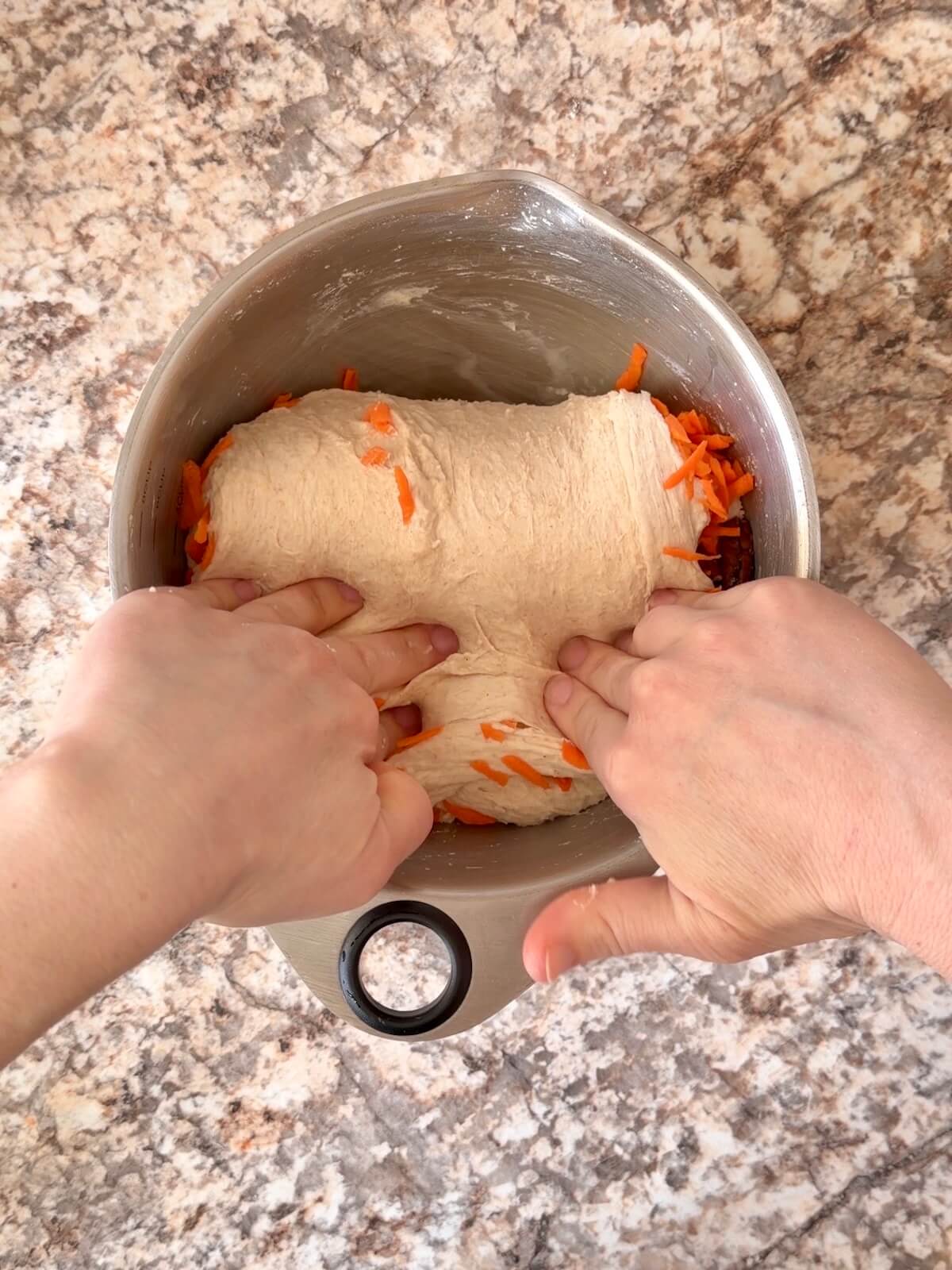 Shredded carrots, raisins, and pecans being folded into the dough.