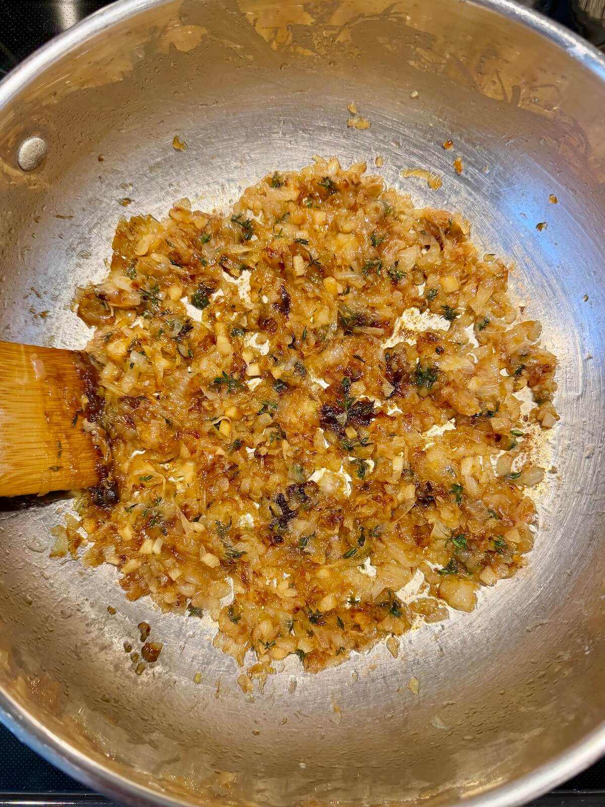Caramelized onions, garlic, and thyme in a stainless steel pot.