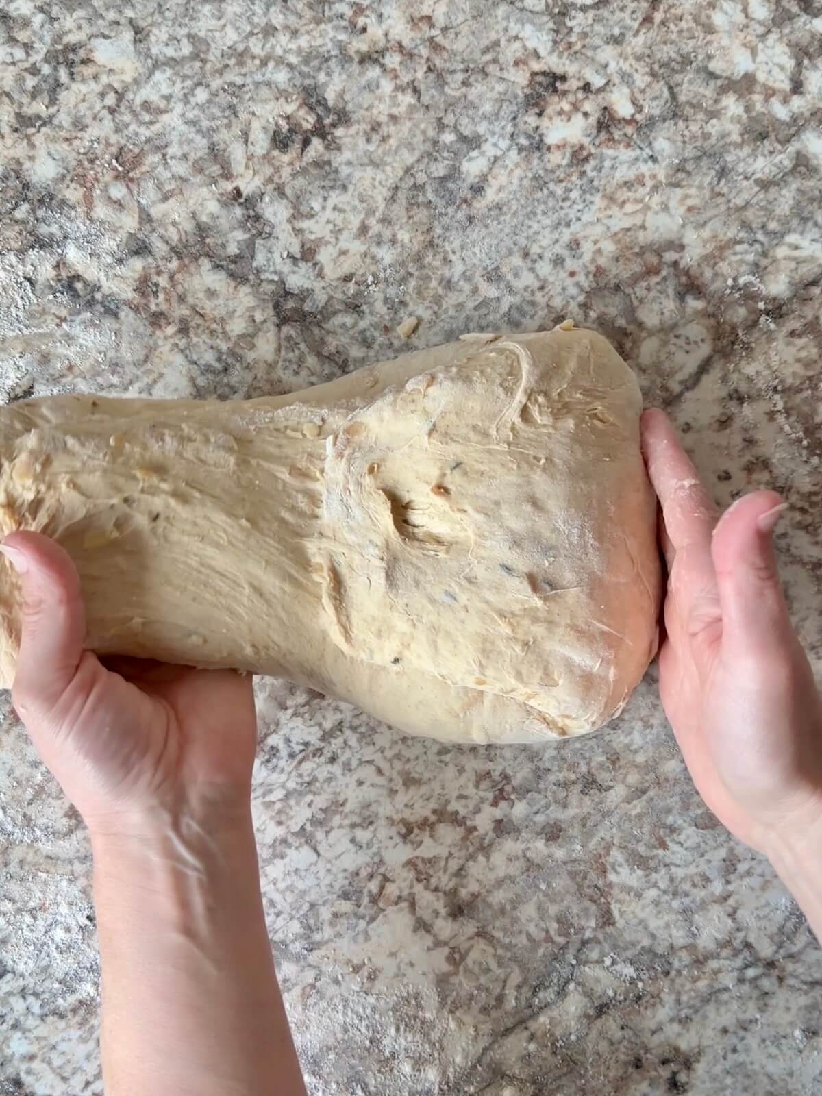 French onion soup sourdough bread dough being shaped on a floured counter.