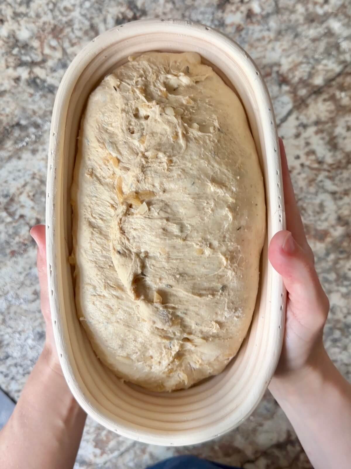 French onion soup sourdough bread dough in an oval proofing basket before cold proofing overnight.