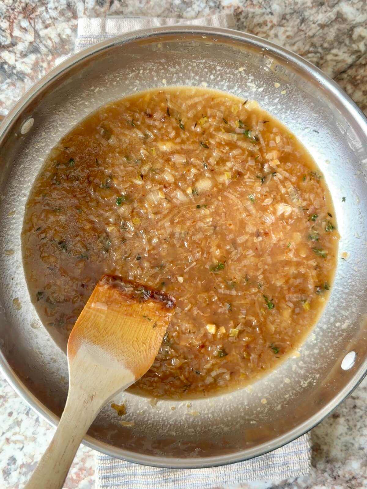 French onion soup in a stainless steel pot.