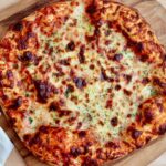 A cheese pizza on a pizza peel made with high-protein sourdough pizza dough.