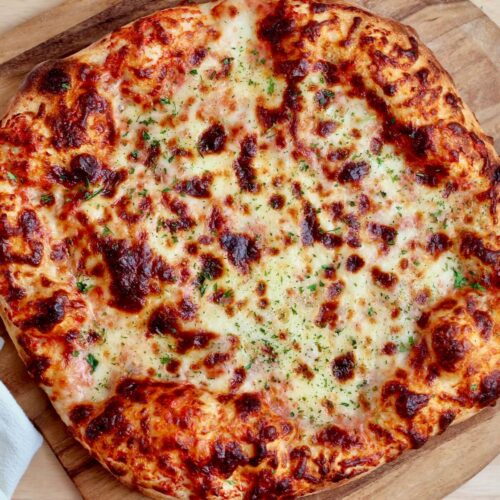 A cheese pizza on a pizza peel made with high-protein sourdough pizza dough.