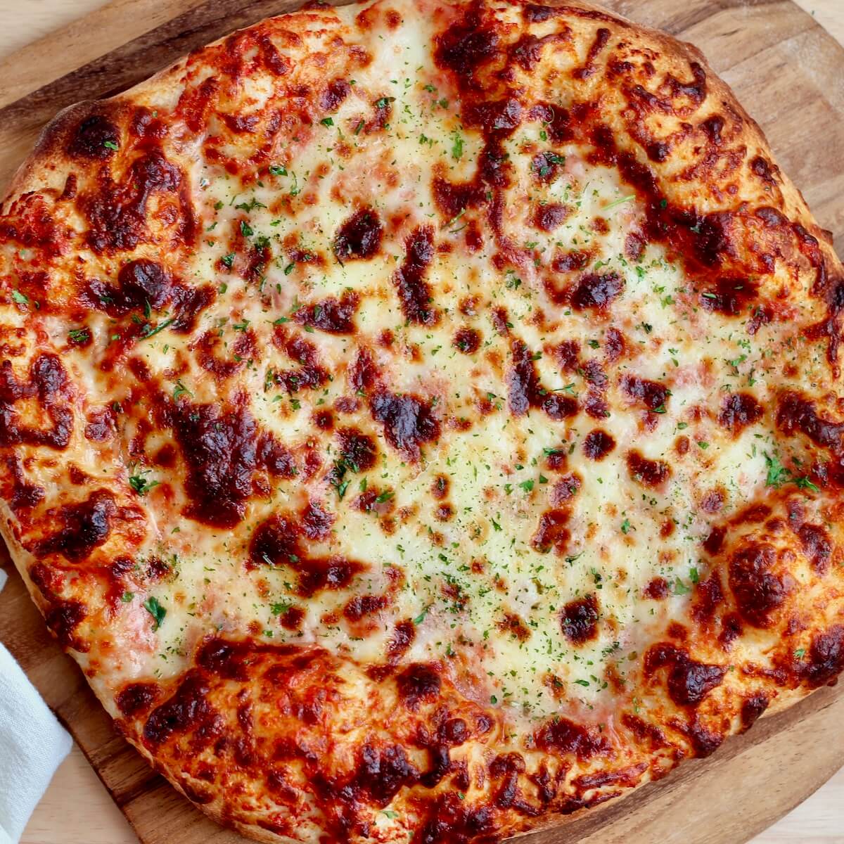 A cheese pizza on a pizza peel made with high-protein sourdough pizza dough.