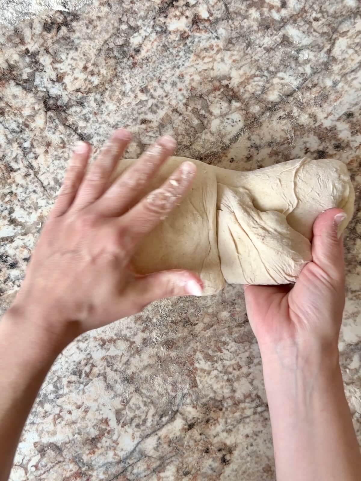 High-protein sourdough pizza dough being shaped on a floured counter.