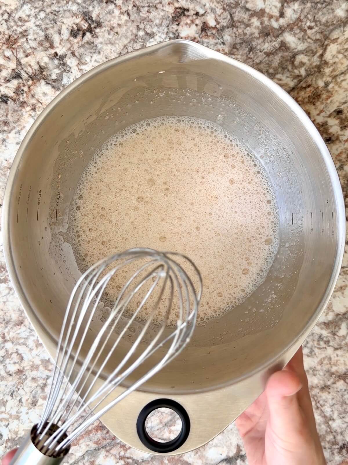 Active sourdough starter and water whisked together in a bowl.