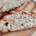 A slice of smoky brown sugar bacon sourdough bread on a cutting board.