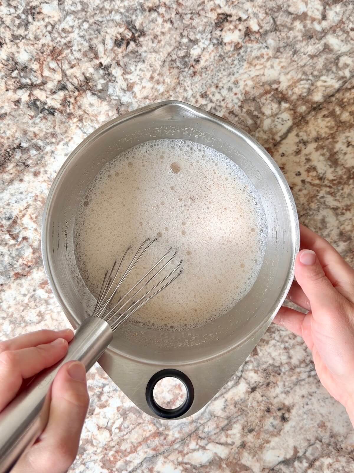 Active sourdough starter and water whisked together in a bowl.