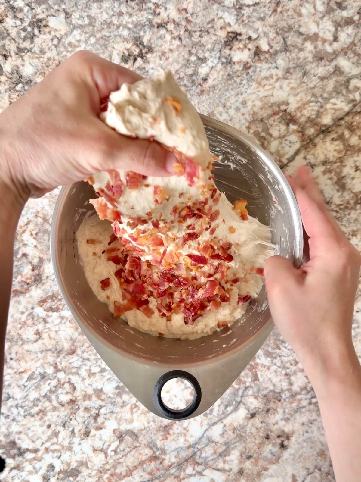 Chopped bacon being folded into sourdough bread dough.