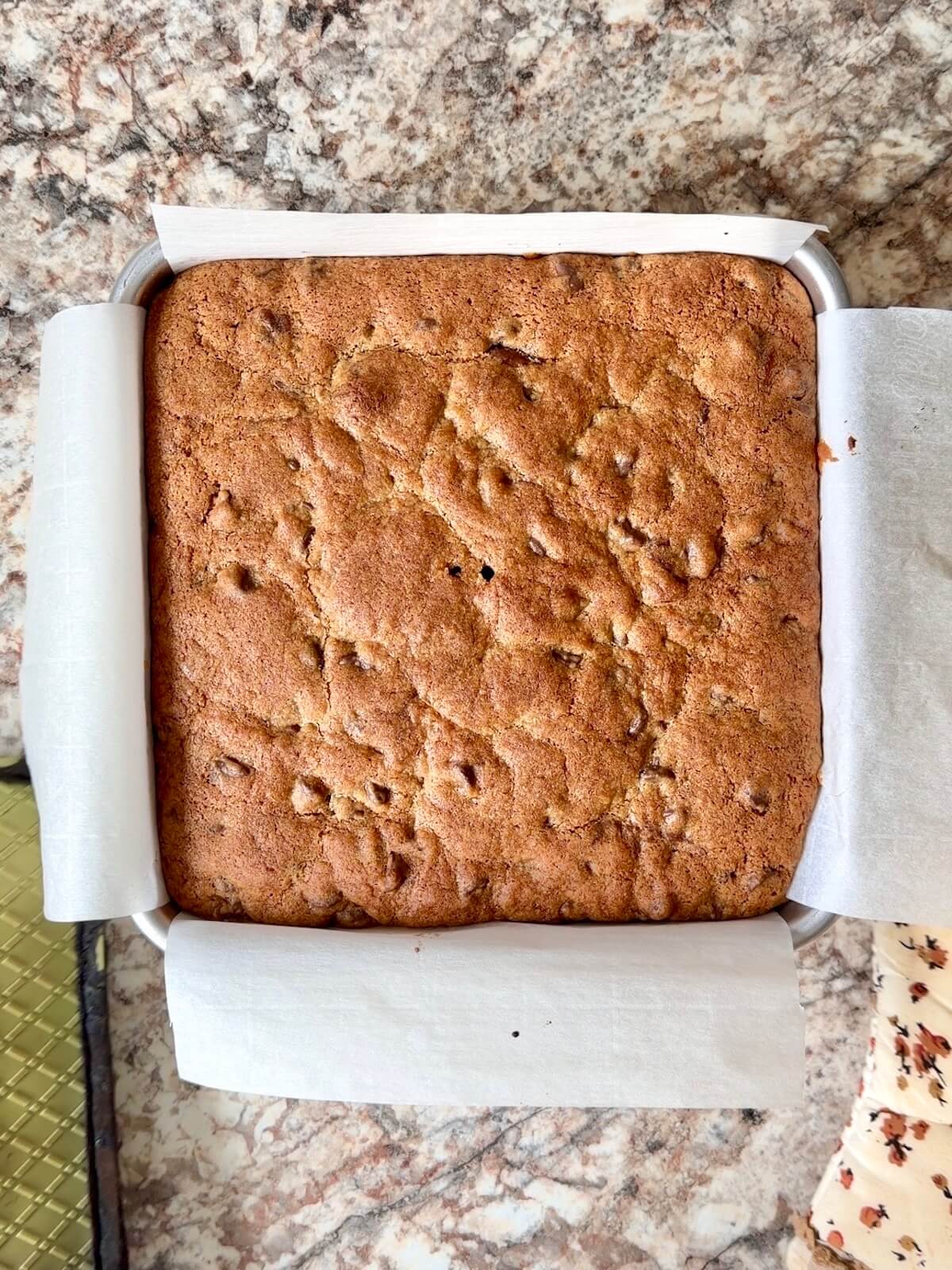 Baked sourdough brookies in a parchment-lined square pan.