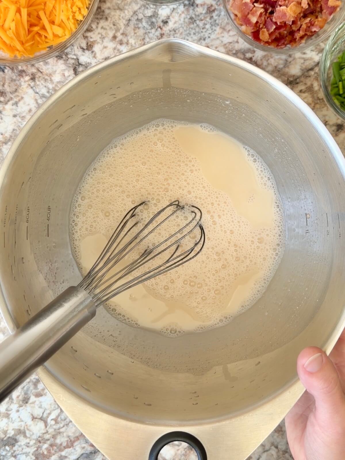 Water and active sourdough starter whisked together in a bowl.