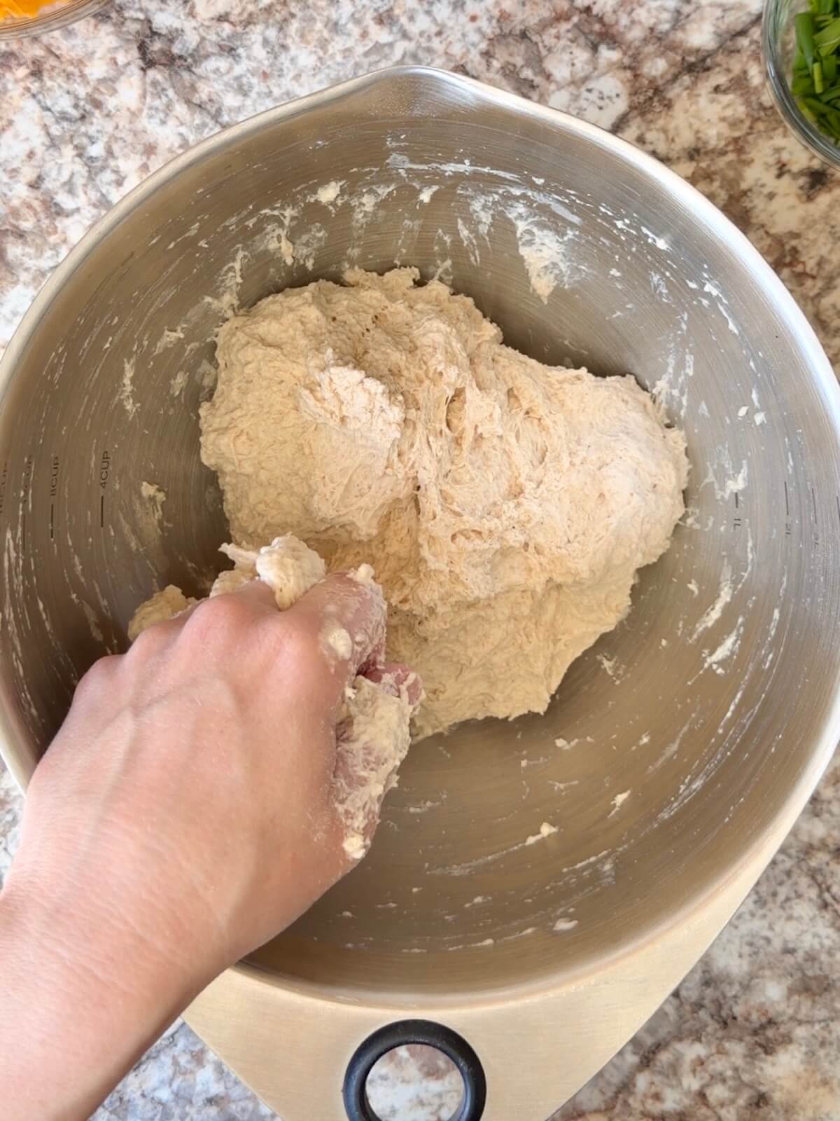 Sourdough bread dough mixed by hand in a bowl.