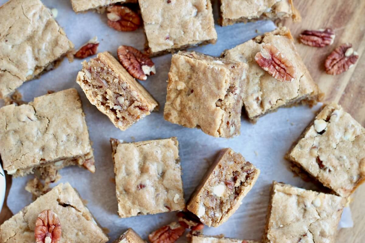 A bunch of sourdough maple pecan bars on a sheet of parchment paper on a counter.