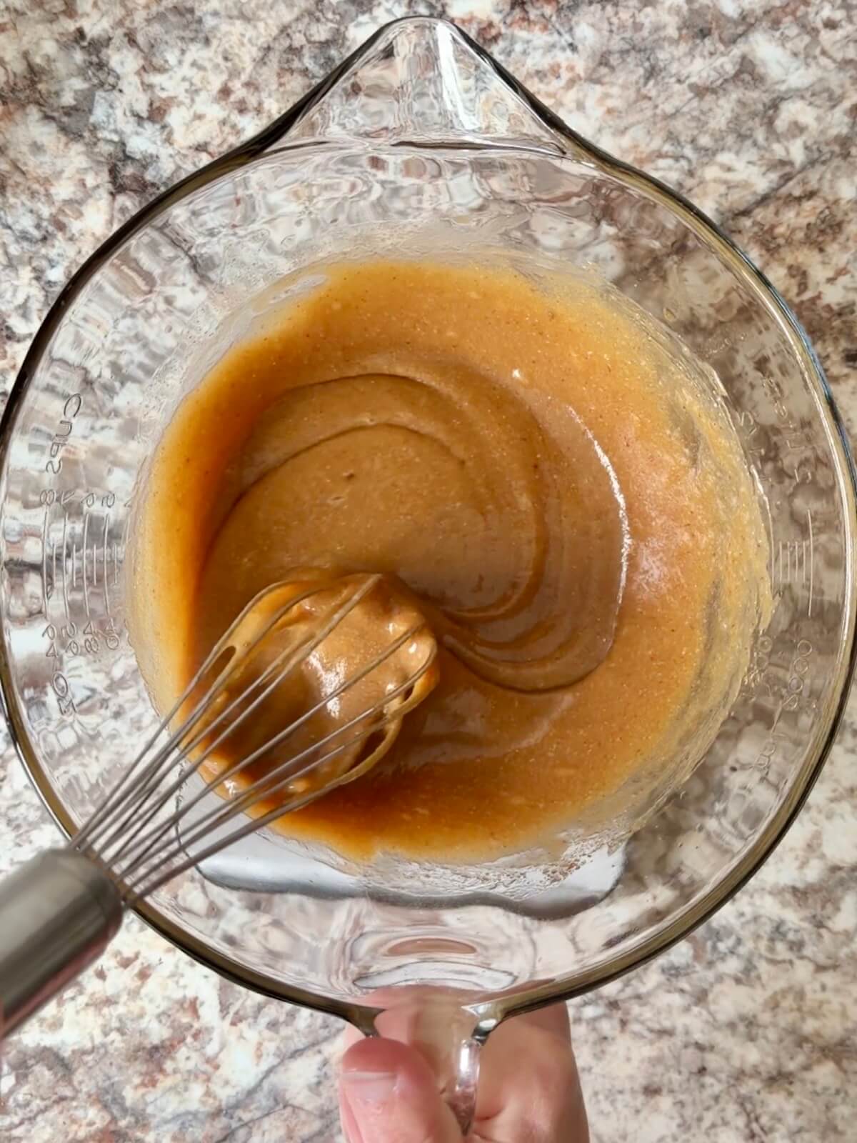 Sourdough discard, maple syrup, and other wet ingredients whisked together in a bowl.