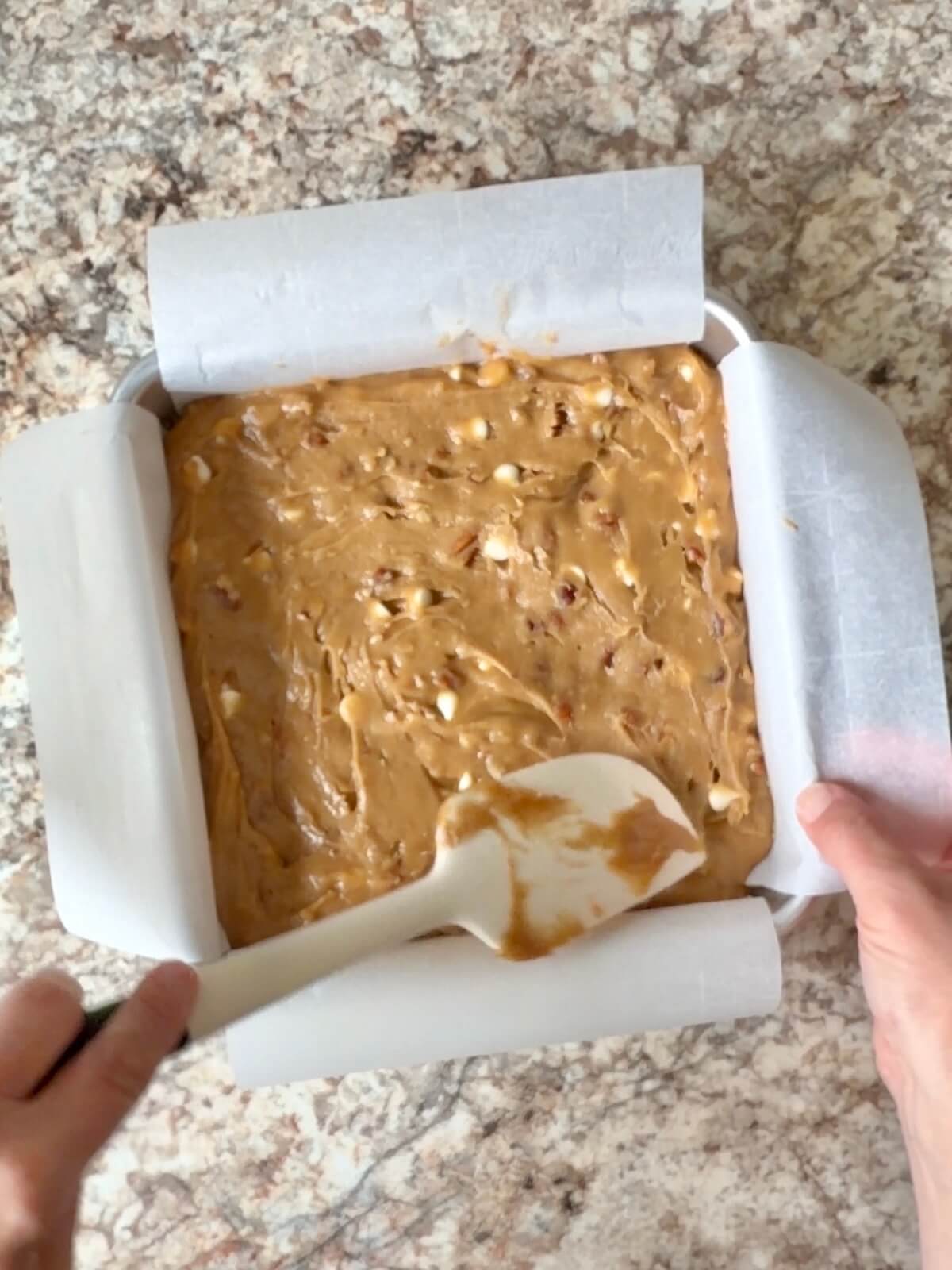 Maple pecan sourdough blondie batter spread in a parchment-lined baking pan.