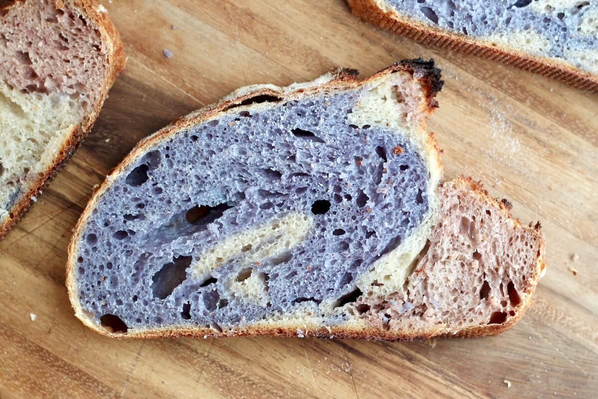 A slice of patriotic sourdough bread on a wooden cutting board.