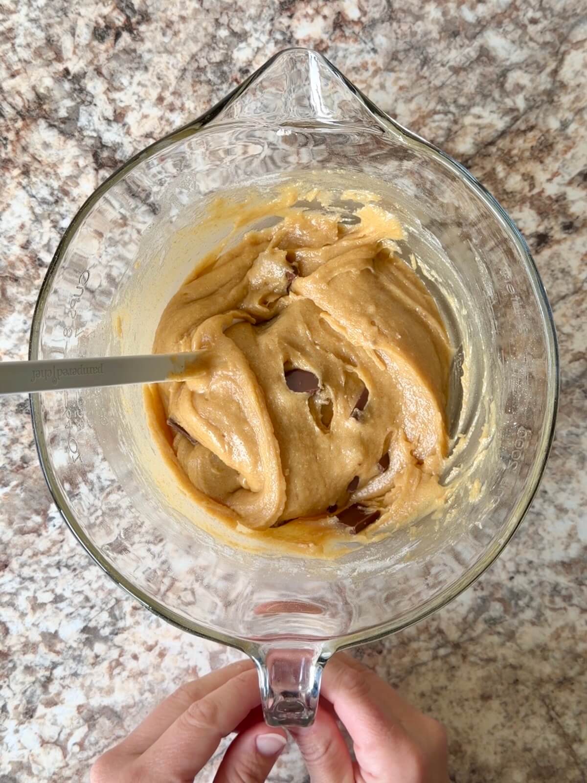 S'mores sourdough blondie batter mixed in a bowl with chocolate bar pieces folded in.
