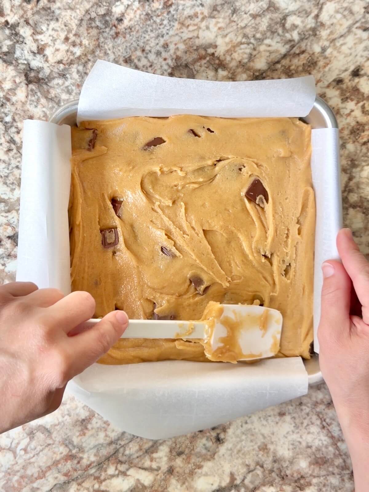 Sourdough s'mores bars batter spread in a square pan lined with parchment paper.