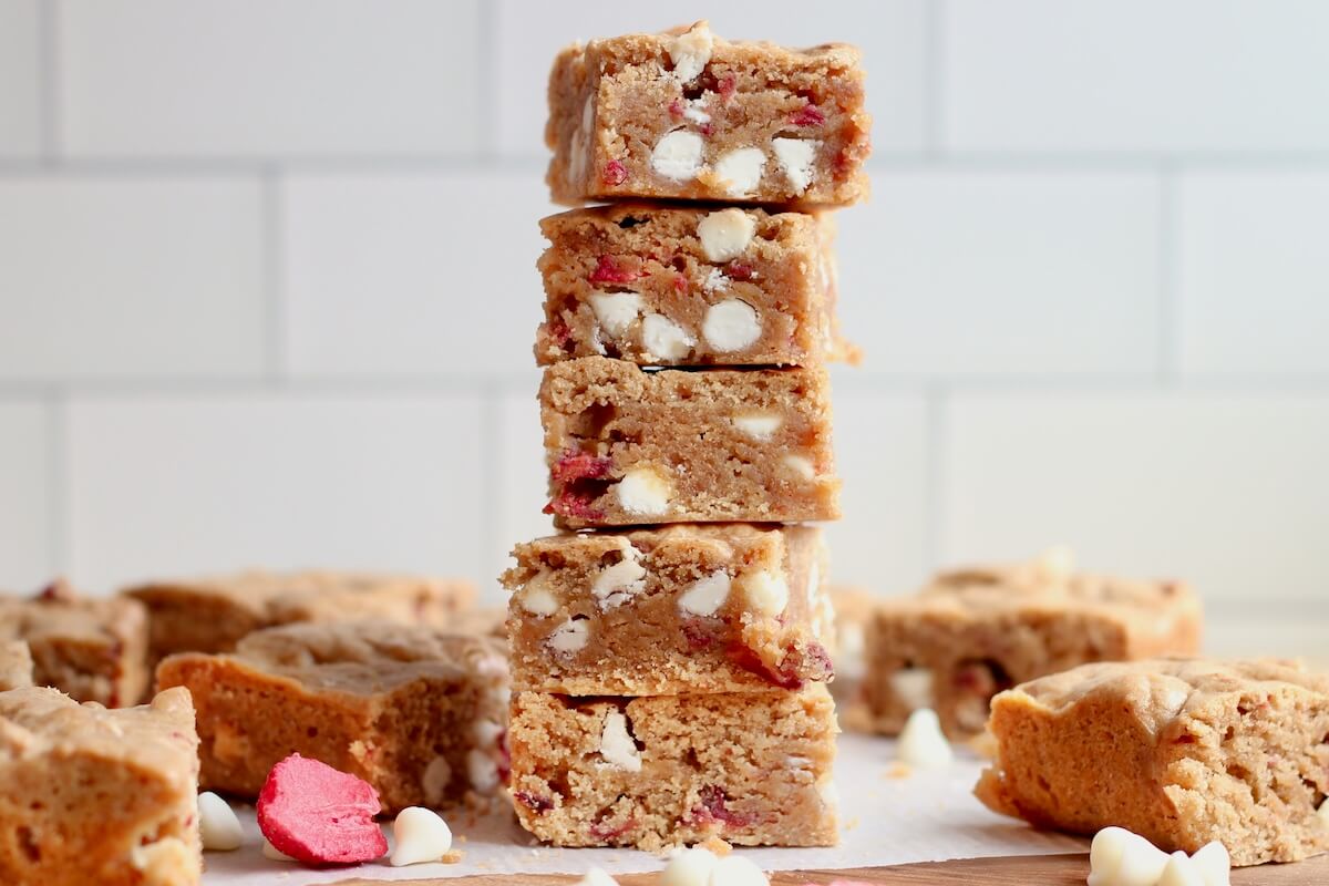 A stack of five sourdough discard strawberry blondies with more blondies out of focus in the background.