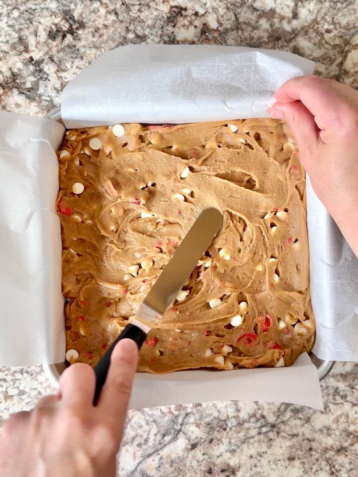 The sourdough blondie batter being spread in a square baking pan.