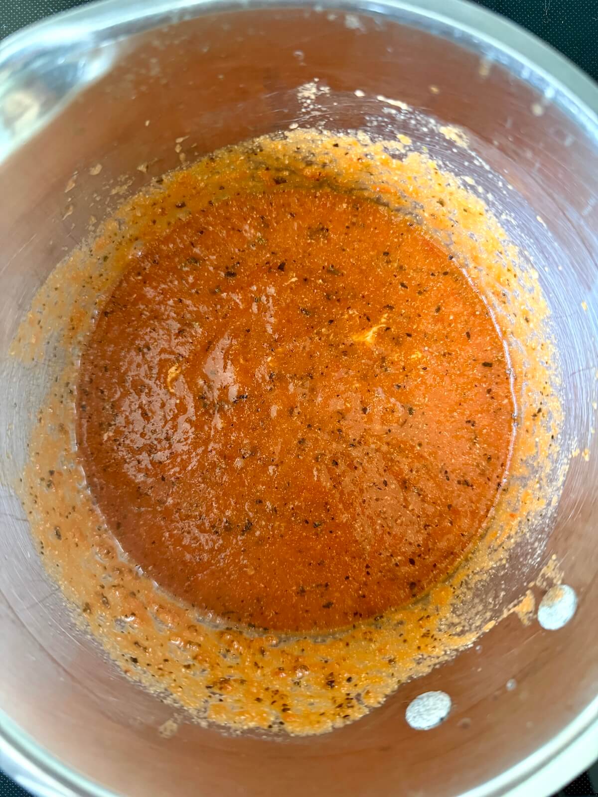 A stainless steel pot of homemade tomato basil soup.