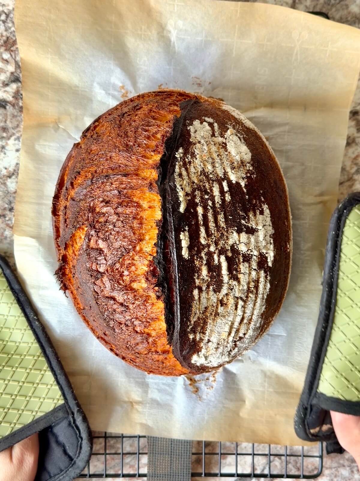 A baked loaf of tomato basil sourdough bread on a wire cooling rack.