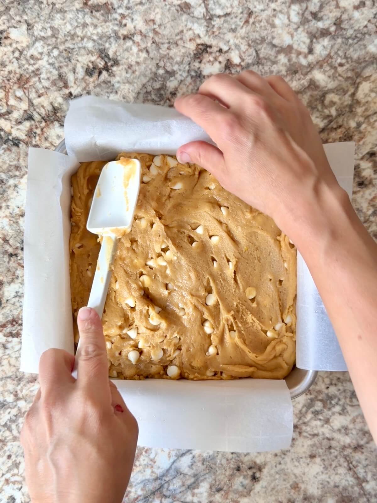 Lemon sourdough blondie batter being spread into a square baking pan.