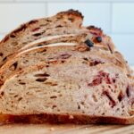 A sliced loaf of peanut butter and jelly sourdough bread on a cutting board.