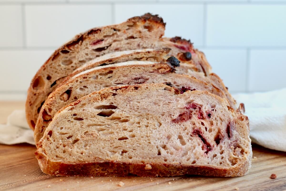 A sliced loaf of peanut butter and jelly sourdough bread on a cutting board.
