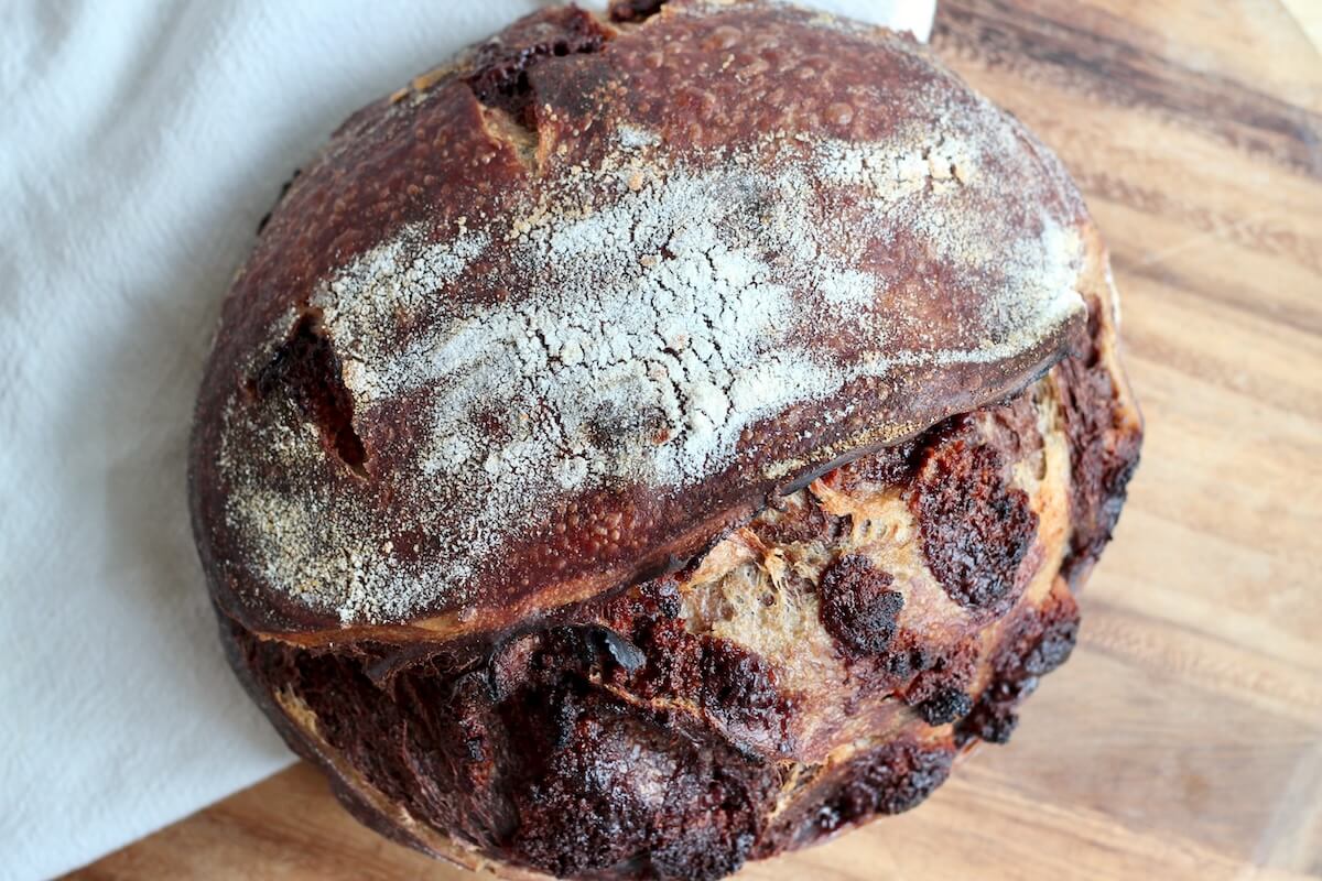 A whole loaf of chocolate peanut butter cup sourdough bread on a cutting board.