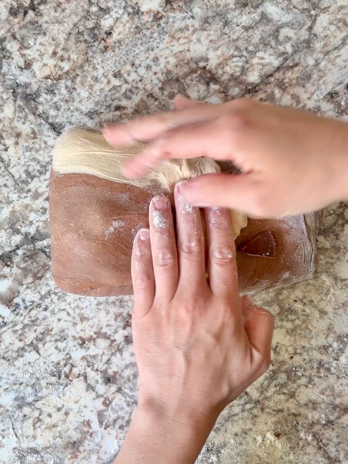 Two hands shaping the peanut butter cup sourdough bread into a dough ball.