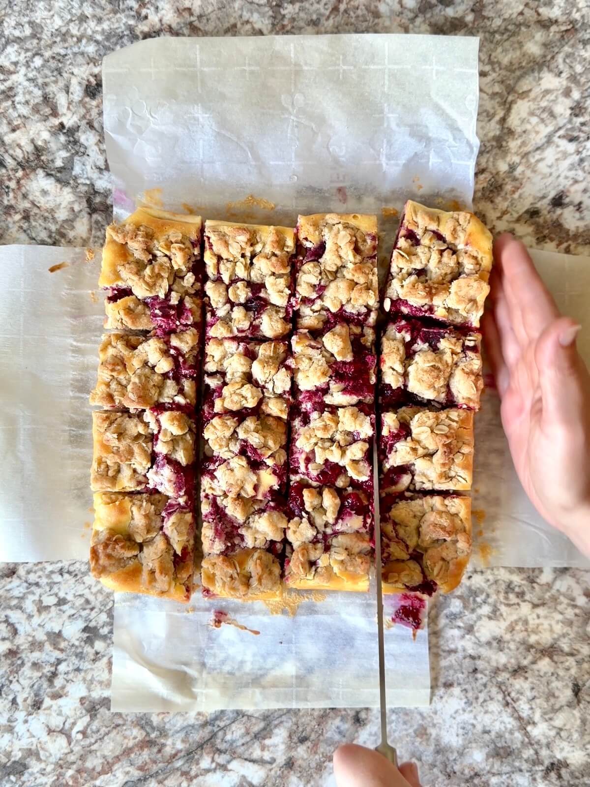 Sourdough raspberry cheesecake bars being cut into 16 squares.