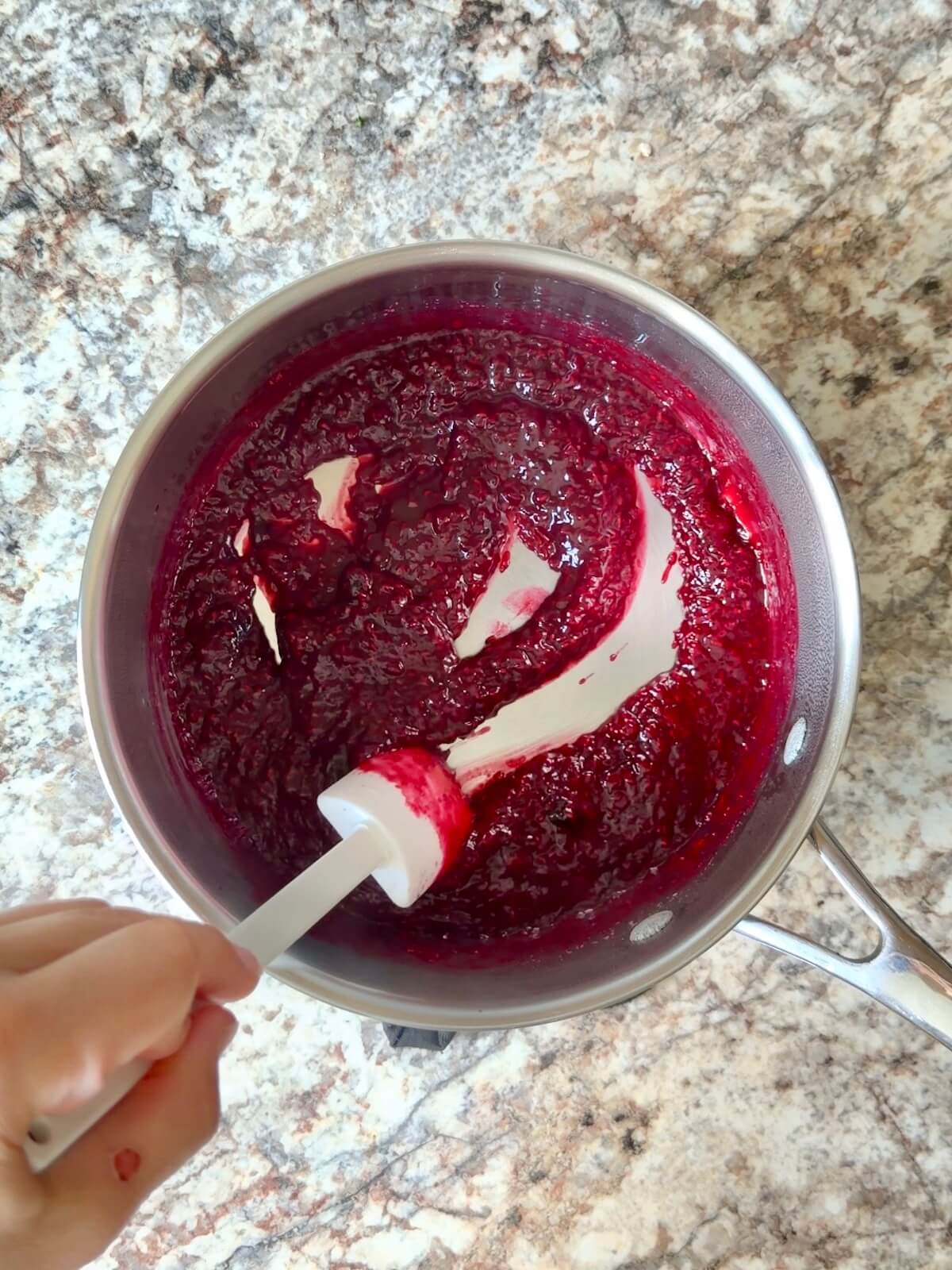 Raspberry sauce in a stainless steel pot.